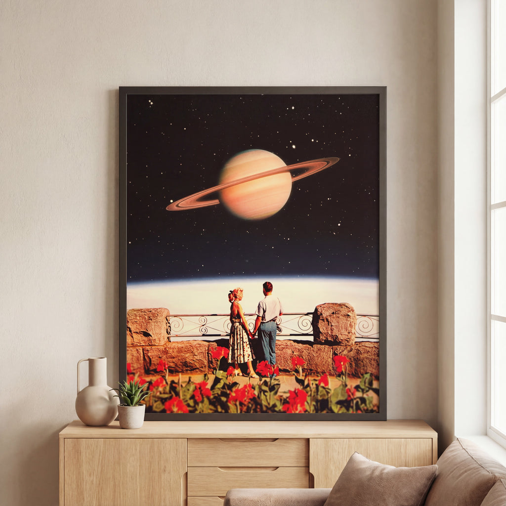 Framed artwork of a couple on a balcony with a planet in the background, displayed on a wall.