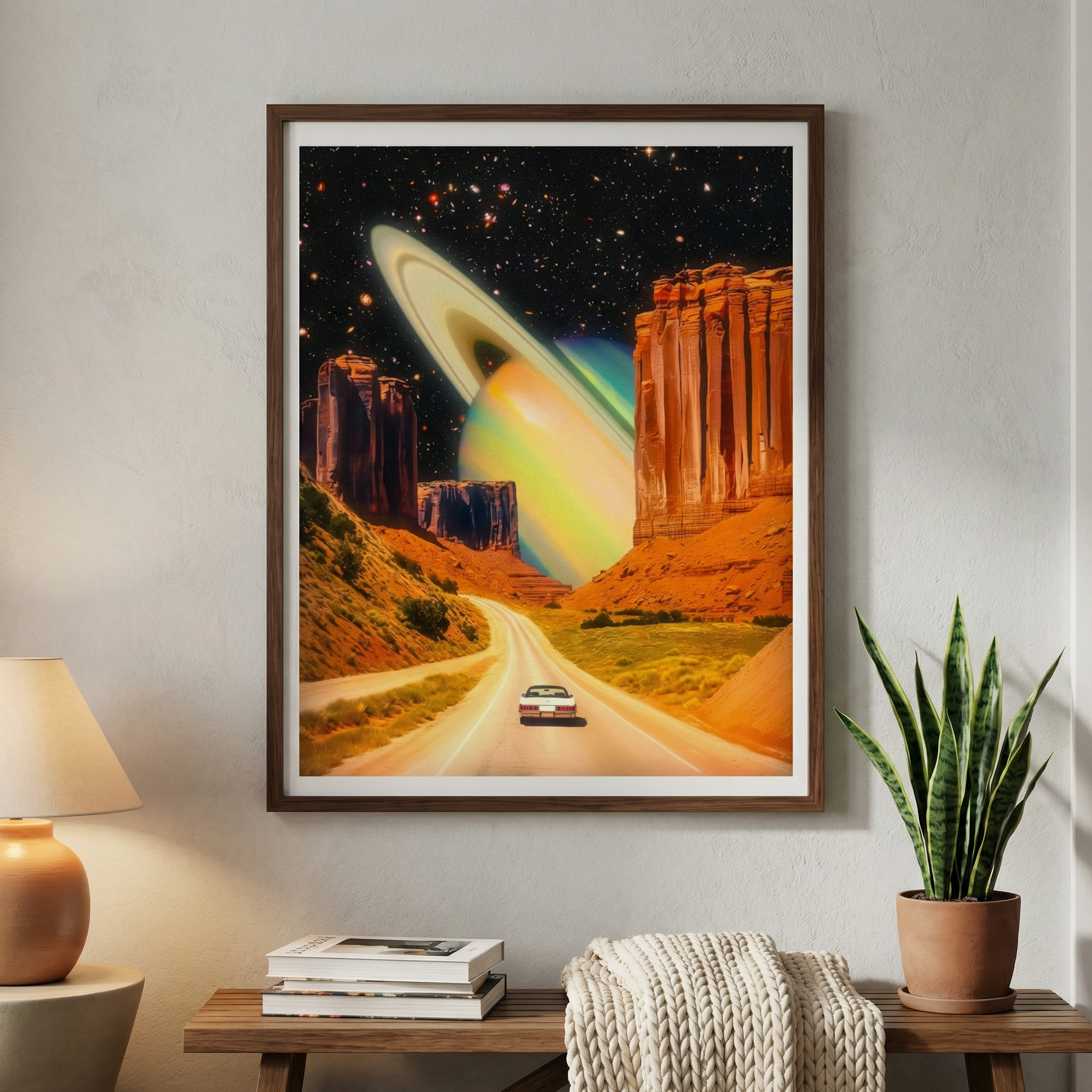 Framed artwork of a desert landscape with a car and celestial body, placed on a wall above a wooden table.
