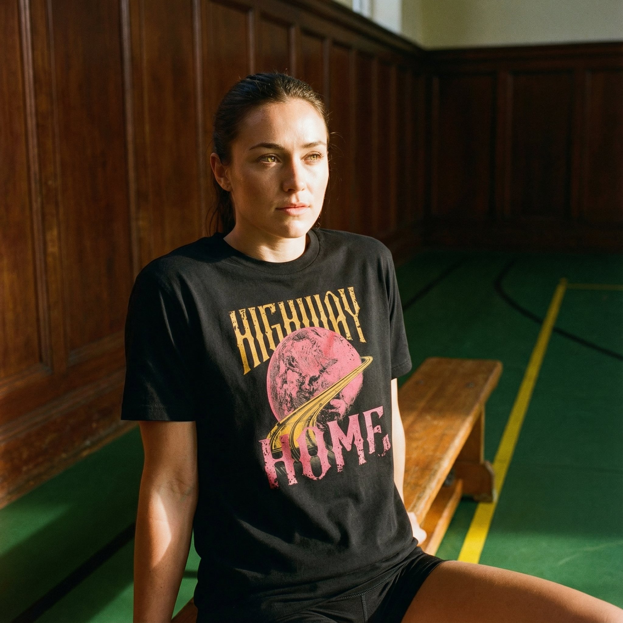 Person wearing a black t-shirt with 'Highway Home' design in a gymnasium.