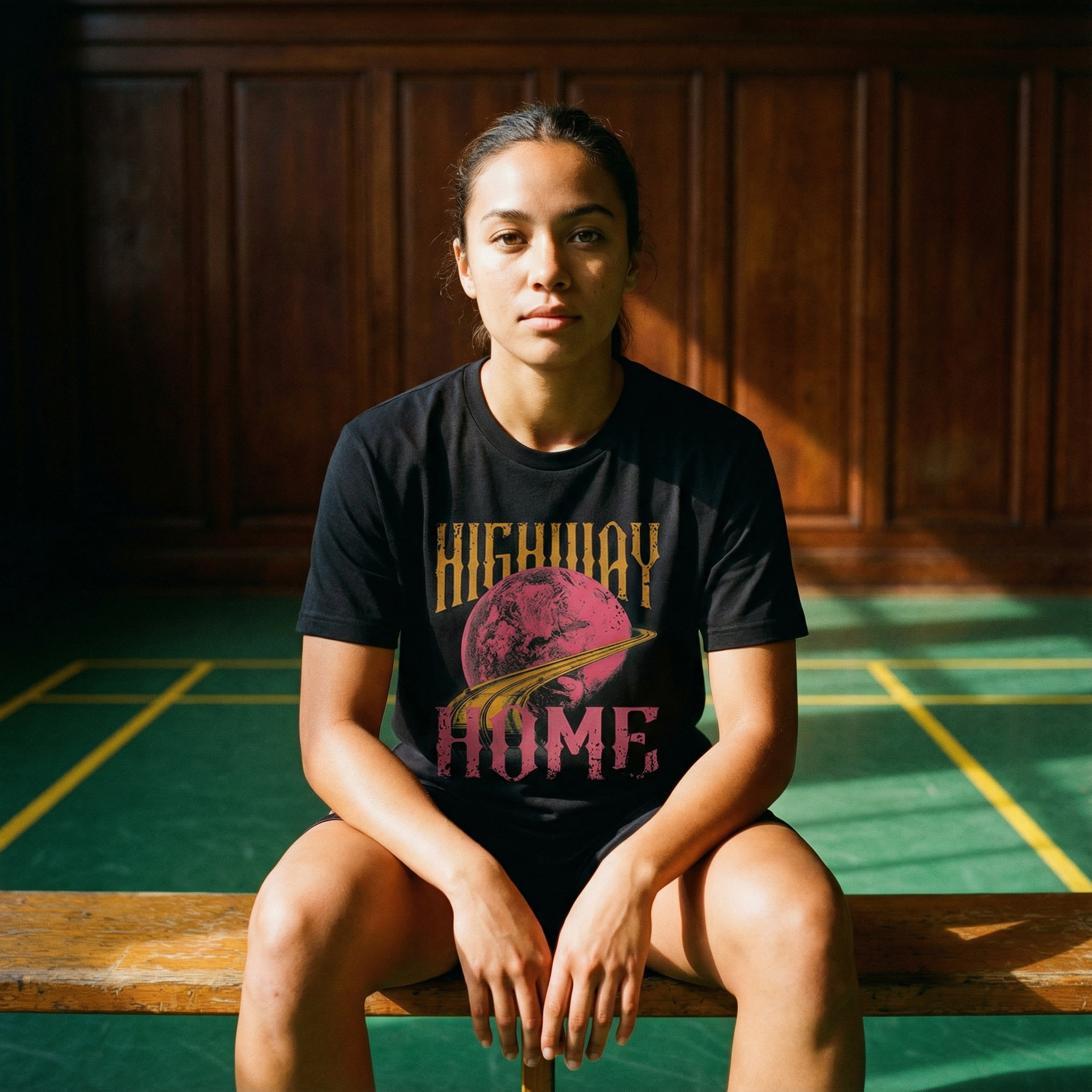 Person wearing a black t-shirt with 'Highway Home' design in a sunlit room.